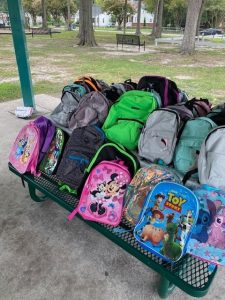 Close-up of colorful backpacks filled with school supplies for a community back-to-school giveaway.
